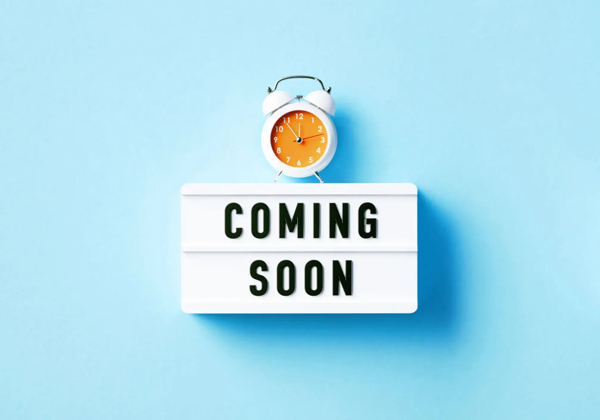 Coming soon sign with orange alarm clock